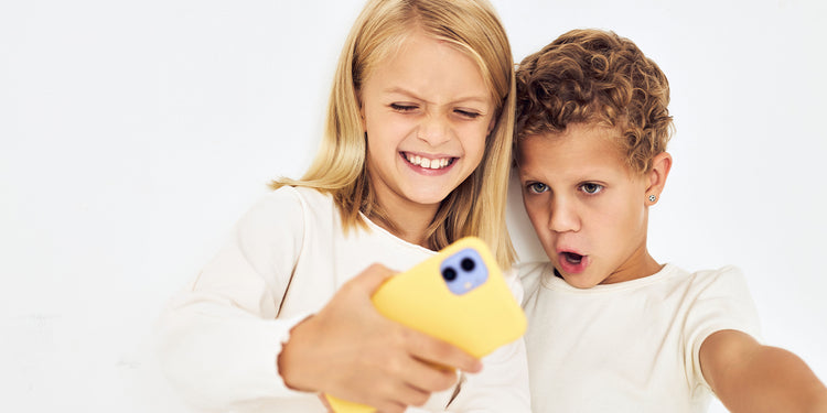 Zwei Kinder machen ein Selfie mit gelbem Handy, beide in weißen T-Shirts